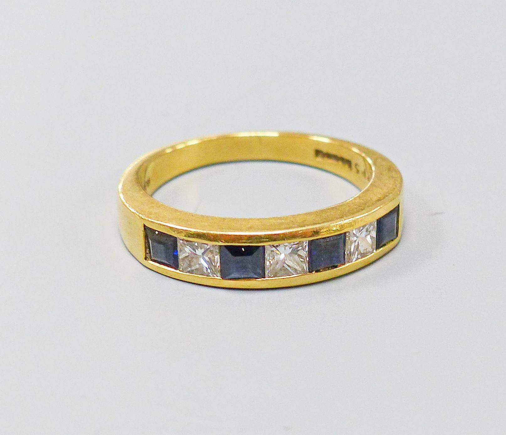 A modern 18ct gold, four stone sapphire and three stone diamond set half hoop ring, size P, gross weight 6.1 grams.